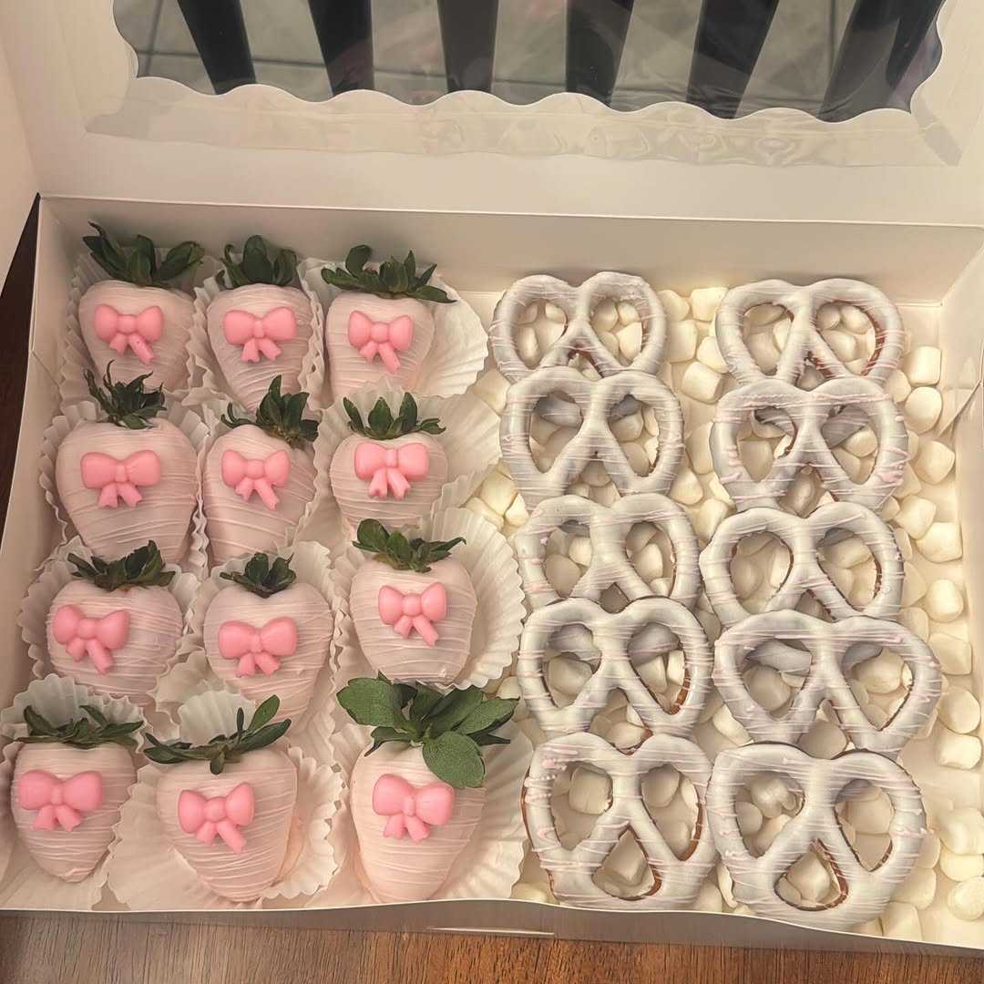 Cohesive pink bow-themed box with ten pink fondant bow strawberries and ten white chocolate pretzels in a strictly pink and white palette with marshmallows.