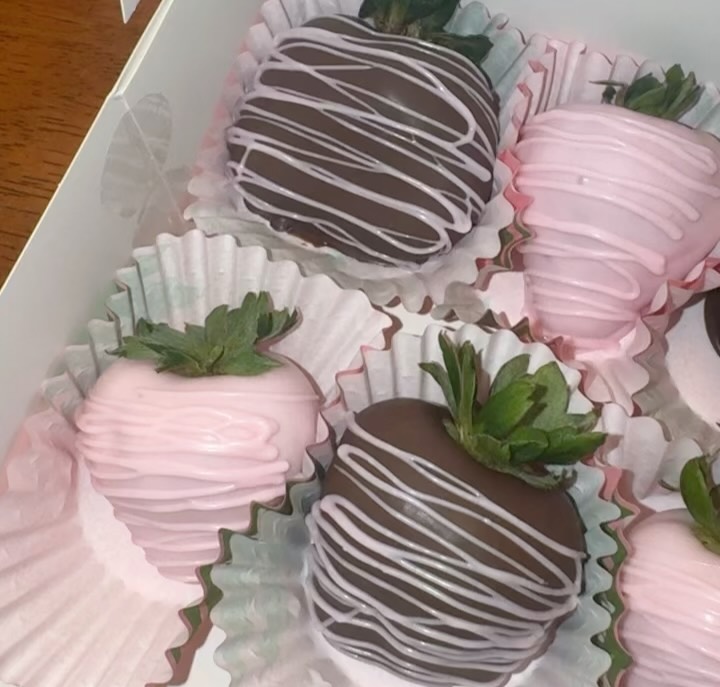 Close-up of alternating pink and dark chocolate strawberries with elegant white chocolate drizzle lines, showing smooth even coatings.