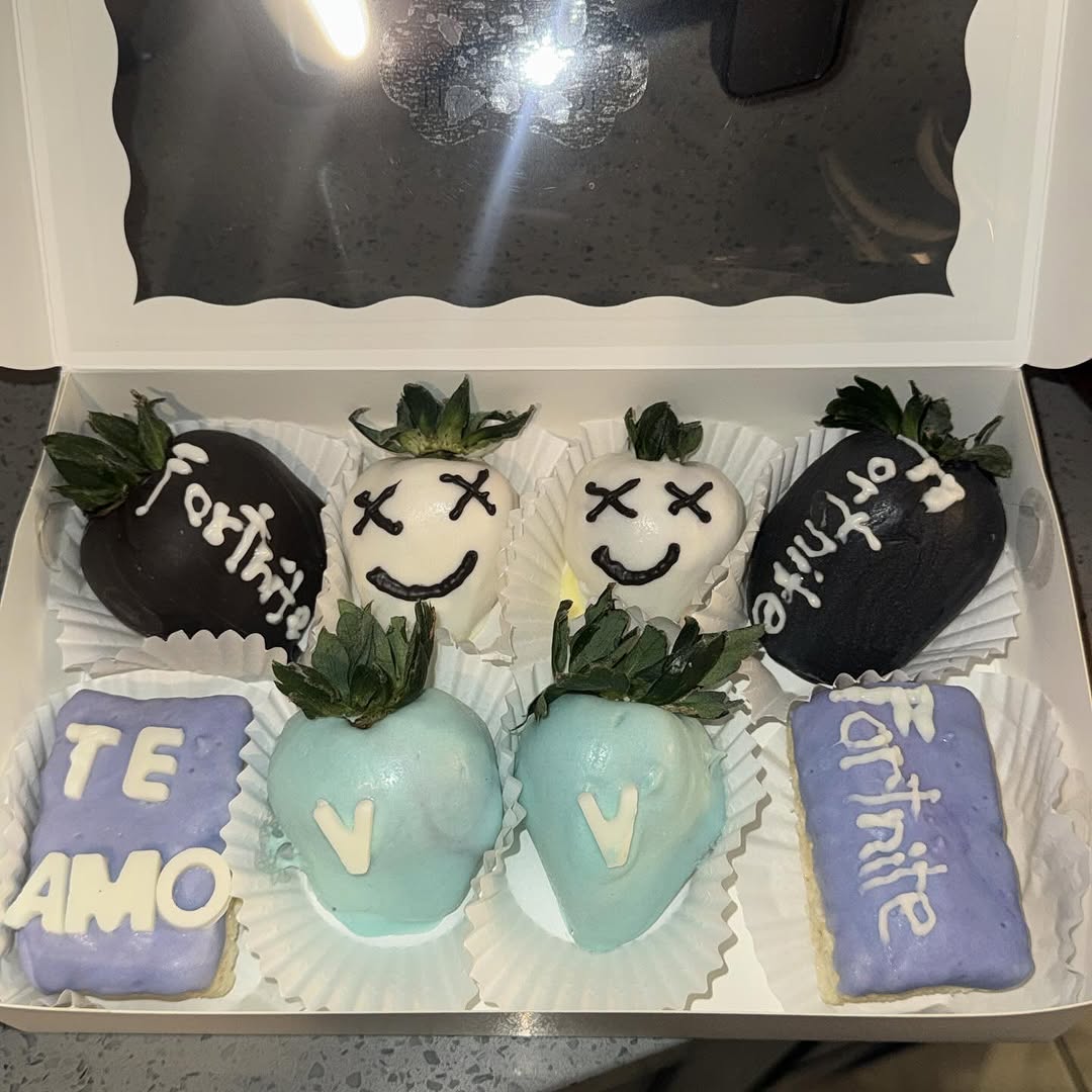 Custom Fortnite and Valentine's themed strawberries and cookies with black Fortnite text, white Marshmello faces, blue V-Bucks designs, and TE AMO cookies.