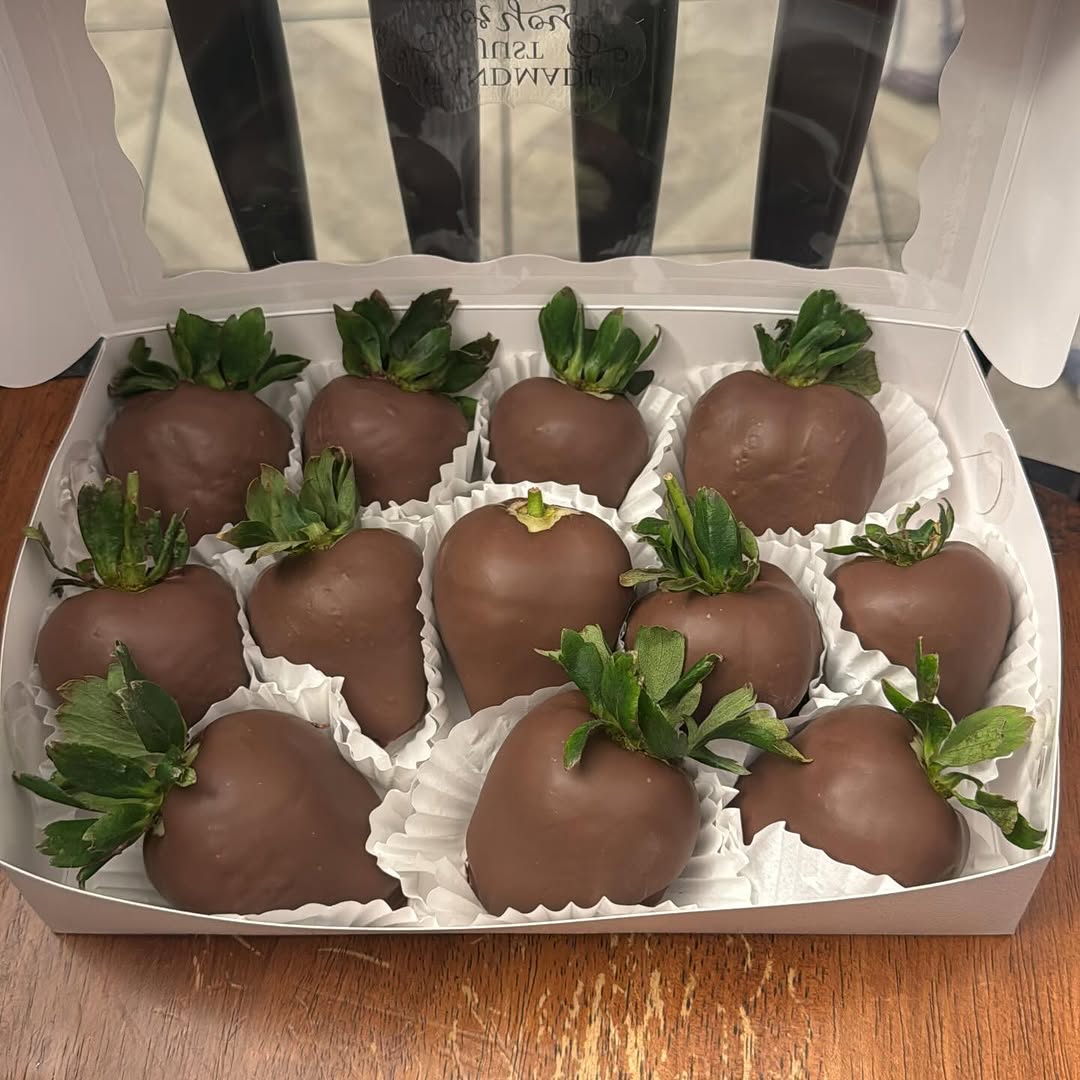 A dozen classic milk chocolate-dipped strawberries in ruffled cupcake liners, a clean and straightforward professional presentation.
